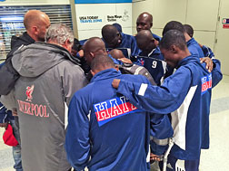 Haiti amputee soccer team prays after arriving at DFW.